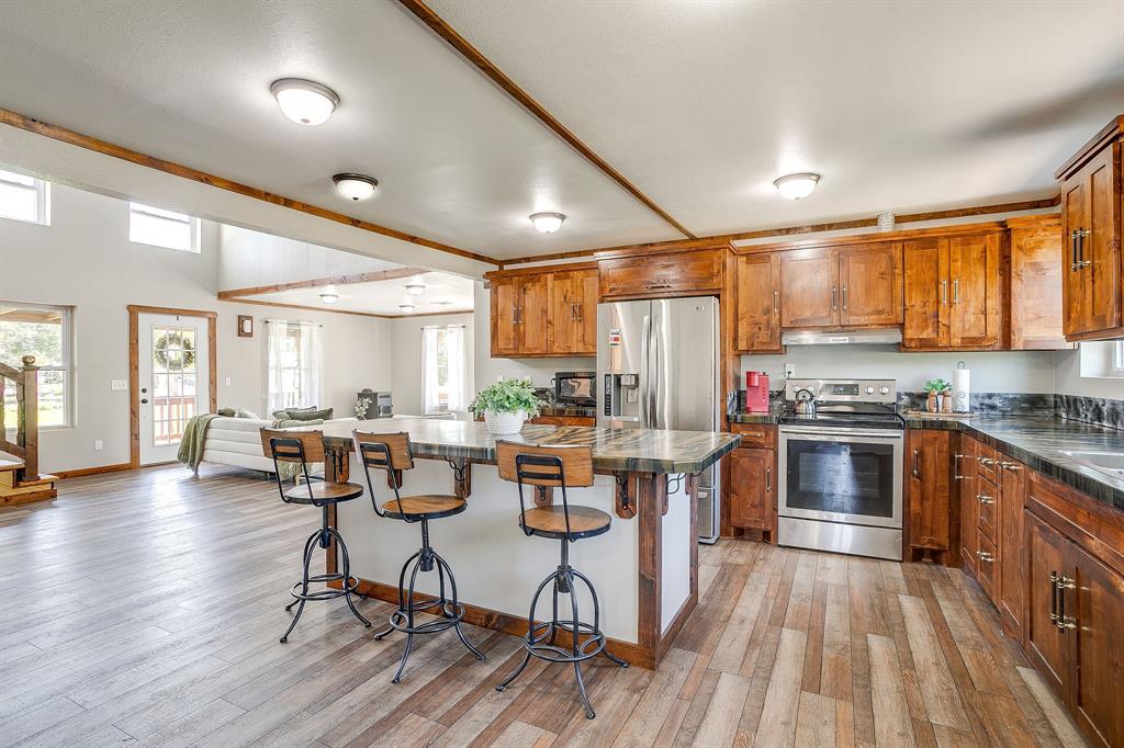 607 East Main Street Itasca, TX 76055 - Photo 14 of 40 a kitchen with stainless steel appliances a stove a sink dishwasher a refrigerator and wooden cabinets with wooden floor