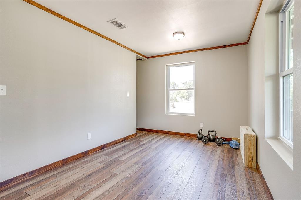 607 East Main Street Itasca, TX 76055 - Photo 24 of 40 an empty room with wooden floor and windows