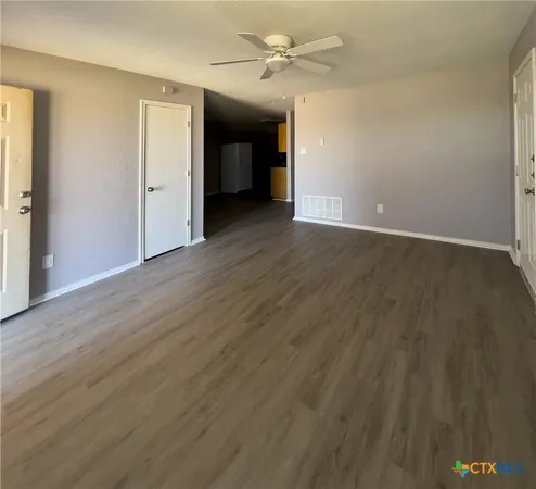 an empty room with wooden floor and ceiling fan