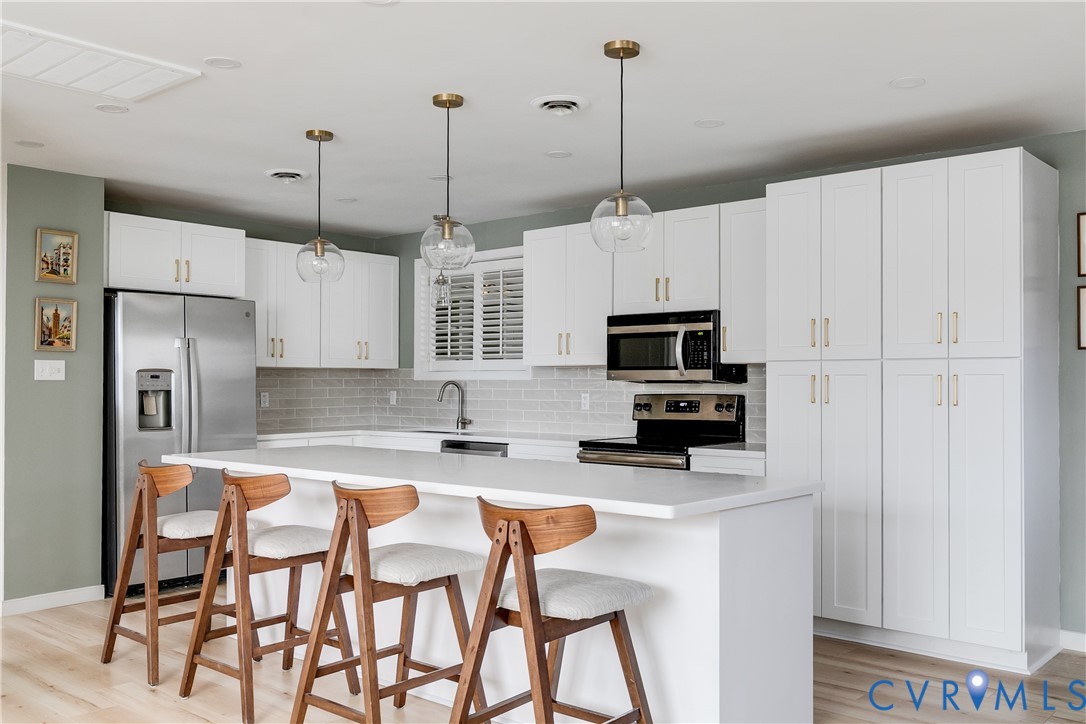 9814 Durango Road Henrico, VA 23228 - Photo 7 of 27 a kitchen with stainless steel appliances kitchen island granite countertop a refrigerator a stove a microwave oven a sink with island and chairs