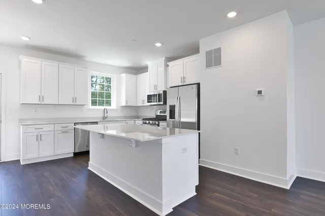 a kitchen with a sink a window a refrigerator and white cabinets