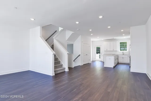 a view of an empty room with wooden floor and stairs