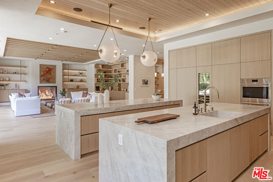 17321 Rancho Street Encino, CA 91316 - Photo 15 of 52 a kitchen with kitchen island granite countertop a sink cabinets and wooden floor
