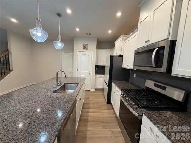 a kitchen with stainless steel appliances granite countertop a stove a sink and a microwave