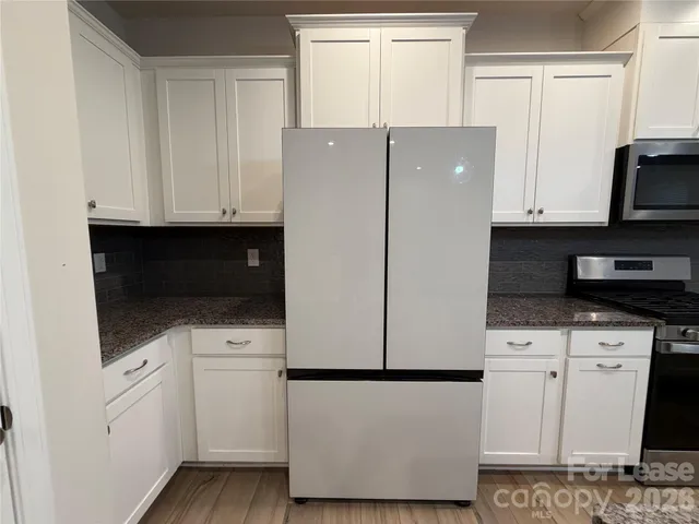 a kitchen with stainless steel appliances white cabinets and a refrigerator