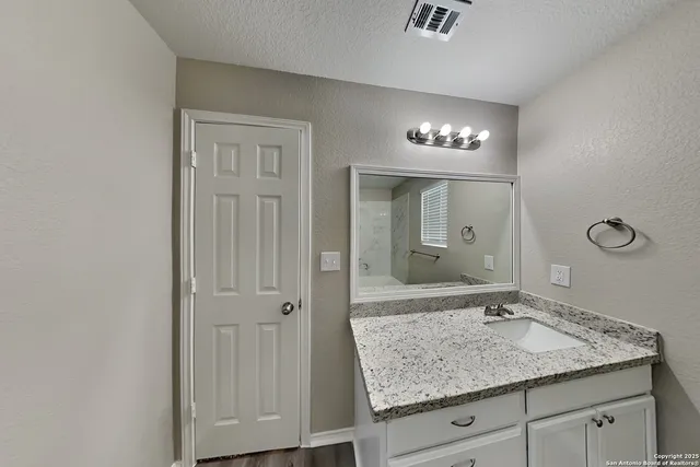 a bathroom with a granite countertop sink and a mirror