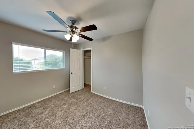 an empty room with a window and a fan