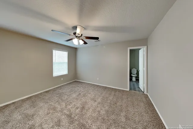 an empty room with windows and fan