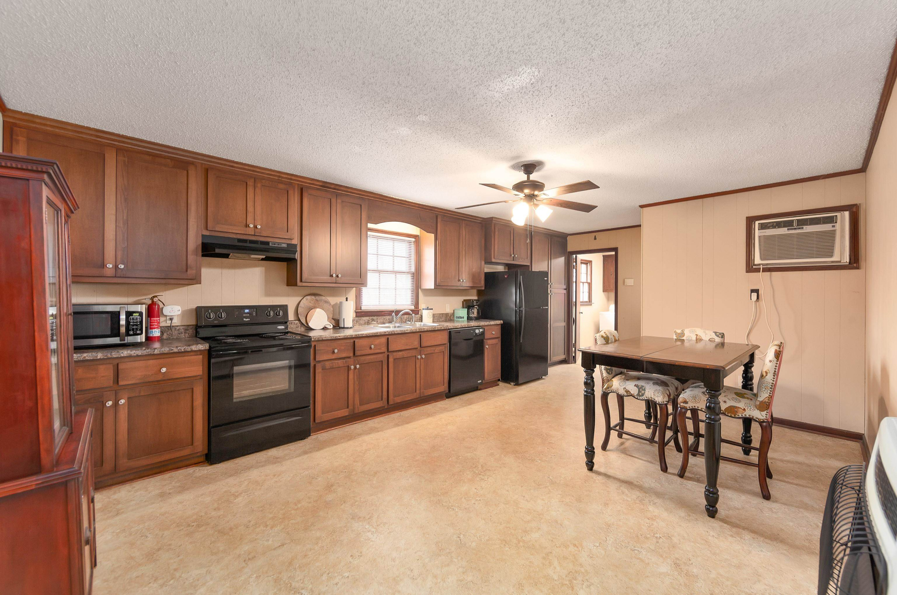 835 Smith Road Luray, TN 38352 - Photo 5 of 19 a kitchen with stainless steel appliances granite countertop a stove top oven a sink dishwasher a dining table and chairs with wooden floor