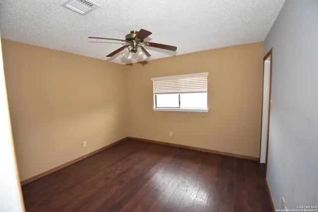 an empty room with wooden floor fan and windows