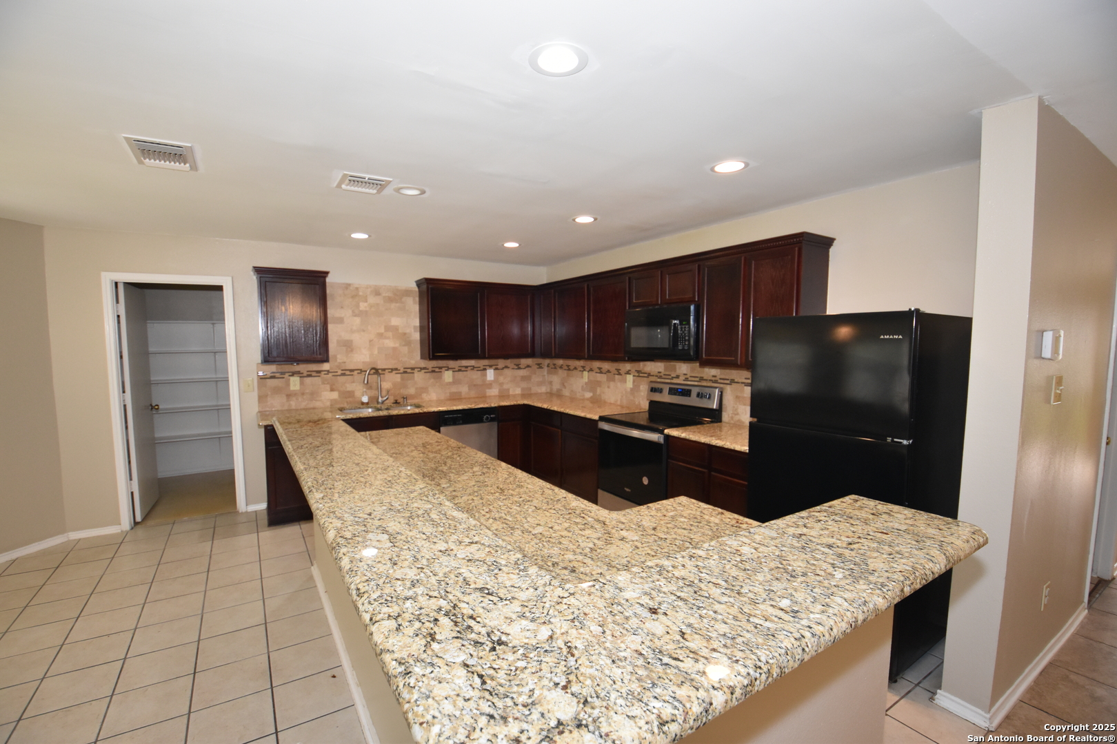 1607 Pinetum Drive San Antonio, TX 78213 - Photo 9 of 26 a kitchen with stainless steel appliances kitchen island granite countertop a refrigerator and a sink