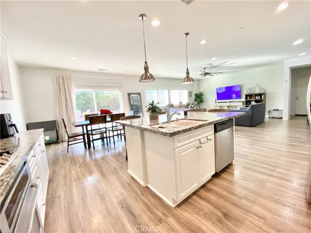 a kitchen with stainless steel appliances granite countertop a dining table chairs refrigerator sink and cabinets