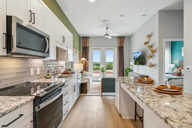 a kitchen with stainless steel appliances granite countertop a stove top oven a sink dishwasher a dining table and chairs with wooden floor