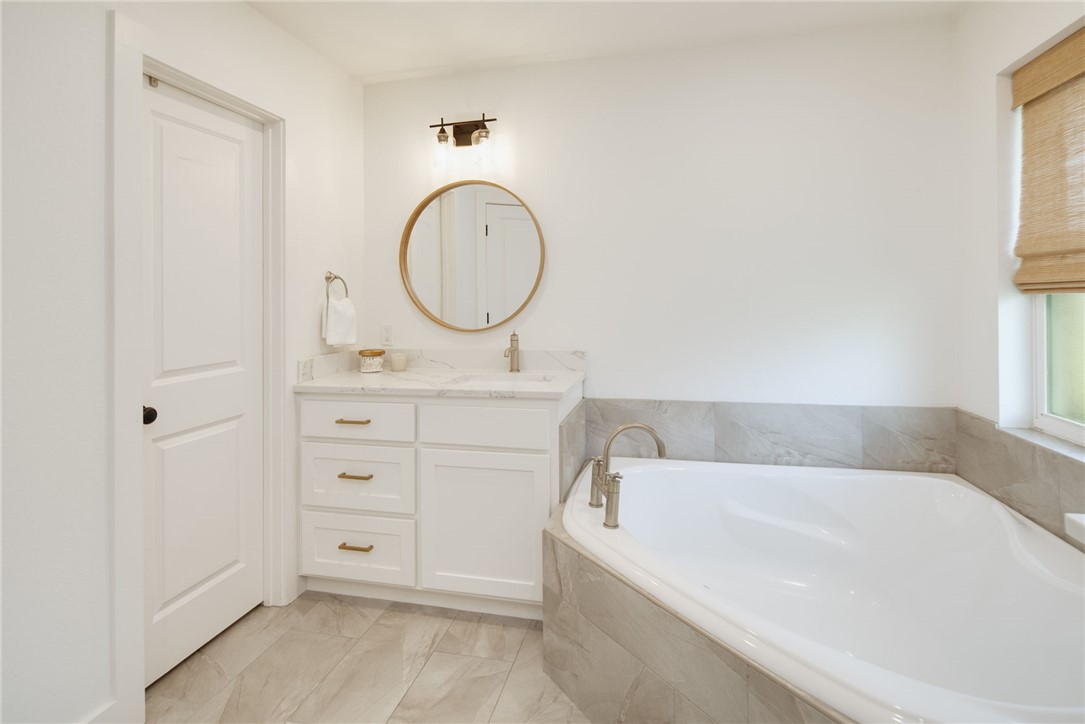 4700 Kensington Road Bryan, TX 77802 - Photo 16 of 31 1 of 2 single vanities with a white countertop and gold-toned hardware, and round mirror