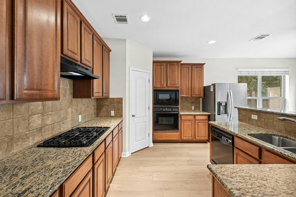 903 Fork Ridge Path Round Rock, TX 78665 - Photo 10 of 35 a kitchen with stainless steel appliances granite countertop a stove top oven a refrigerator a sink and dishwasher
