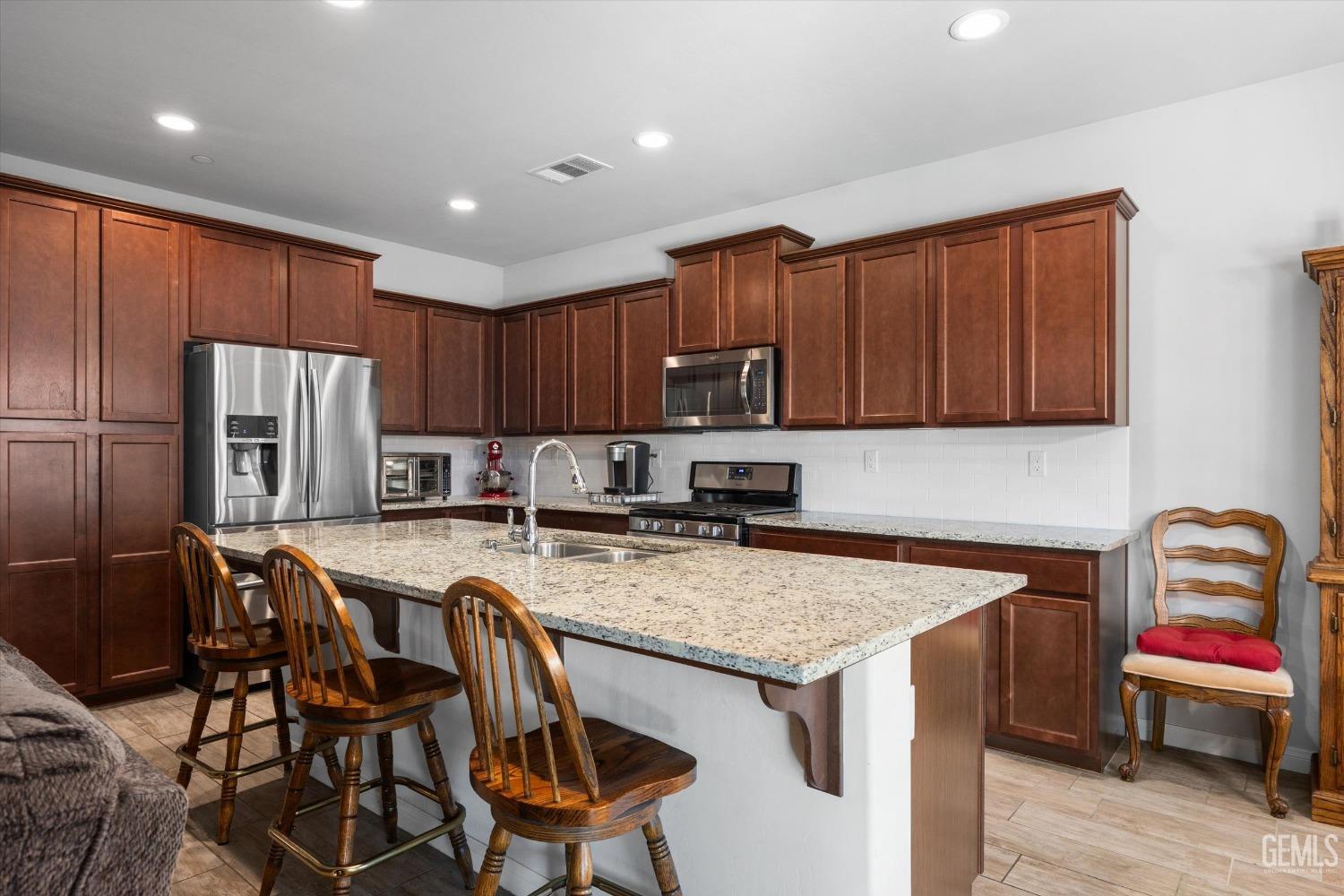Undisclosed Address Bakersfield, CA 93313 - Photo 7 of 24 a kitchen with a stove a refrigerator and a table with chairs