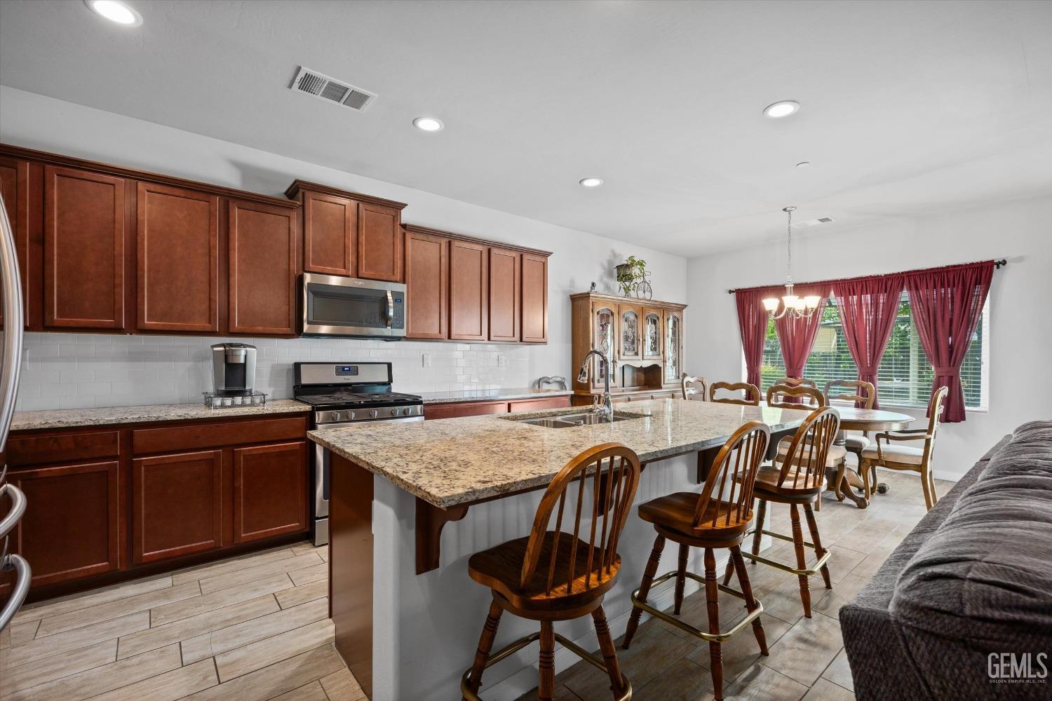 Undisclosed Address Bakersfield, CA 93313 - Photo 8 of 24 a kitchen with stainless steel appliances granite countertop table chairs sink and cabinets
