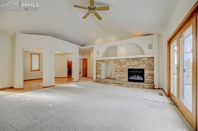 15091 Ridgefield Lane Colorado Springs, CO 80921 - Photo 5 of 35 Unfurnished living room with ceiling fan, lofted ceiling, a fireplace, and light carpet