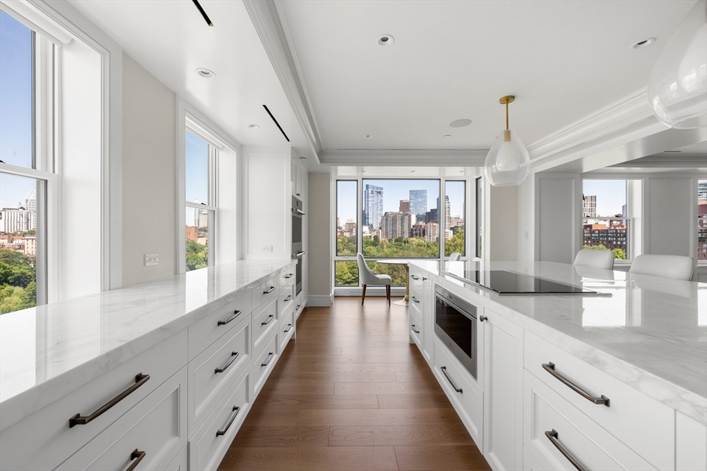2 Commonwealth Avenue, Unit 11BCD Boston, MA 02116 - Photo 12 of 39 a large white kitchen with granite countertop a large window and stainless steel appliances