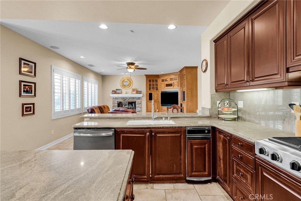 2542 Adage Way Riverside, CA 92506 - Photo 18 of 59 a kitchen with stainless steel appliances granite countertop a stove a sink dishwasher and a microwave oven with wooden cabinets