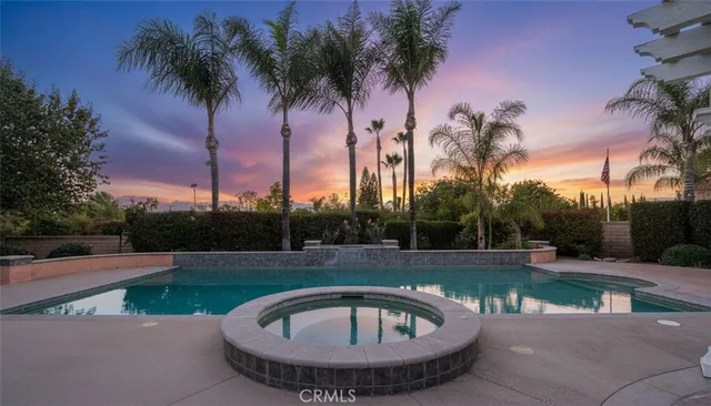 a view of a patio with a dining table and chairs under an umbrella with large trees and big yard