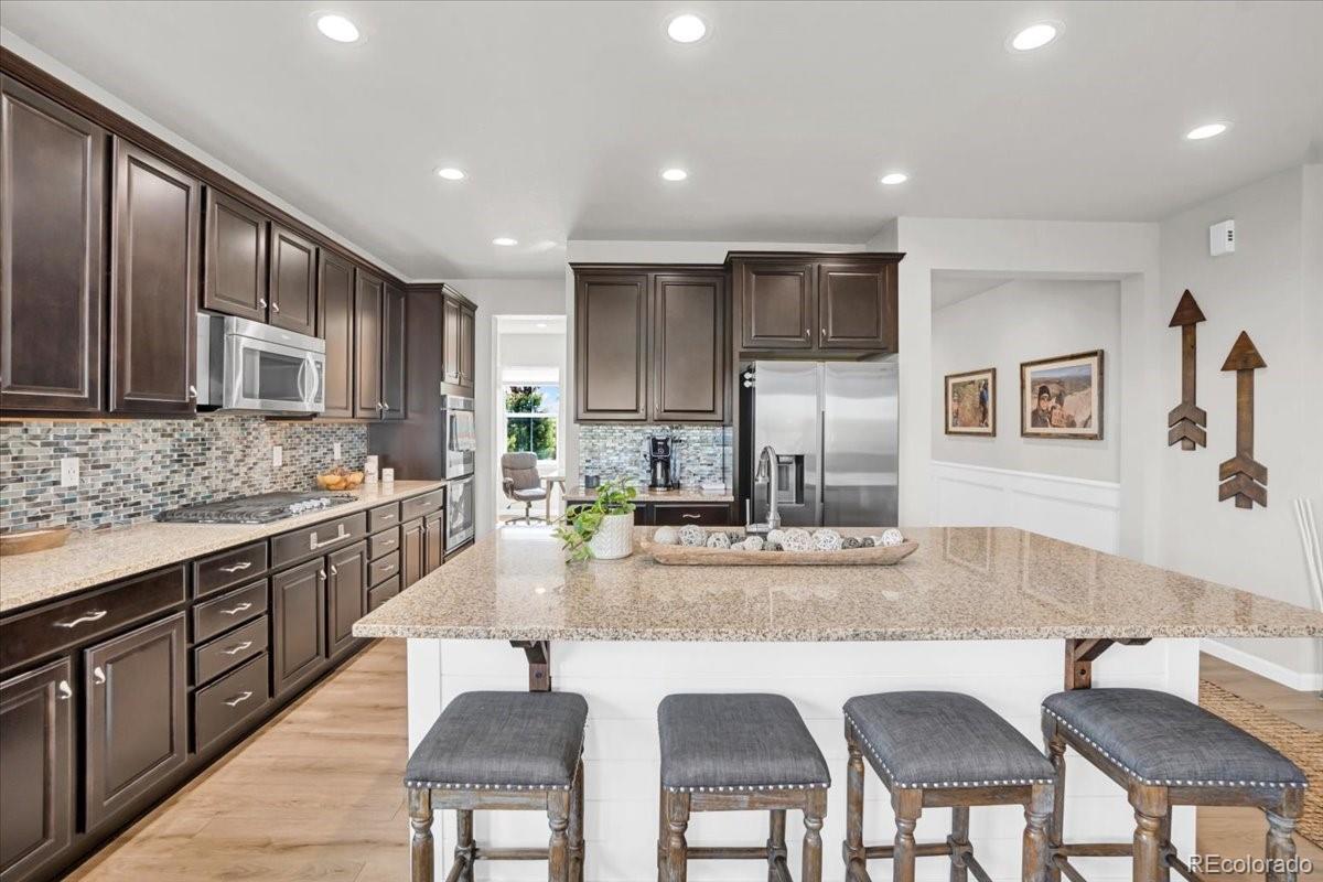 1767 Ghost Dance Circle Castle Rock, CO 80108 - Photo 10 of 48 a kitchen with stainless steel appliances granite countertop a table chairs sink refrigerator and cabinets