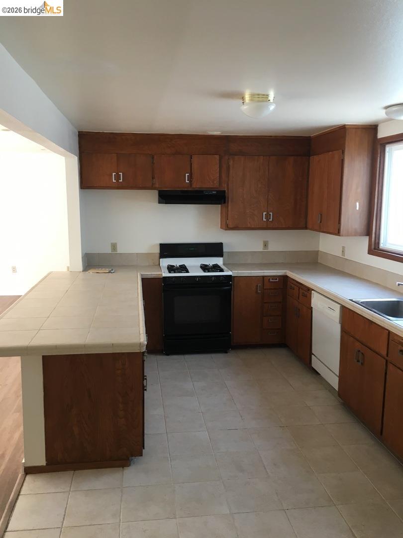 1641 Walnut Street Berkeley, CA 94709 - Photo 11 of 11 kitchen featuring a peninsula, black range with gas stovetop, tile countertops, dishwasher, and light tile patterned floors