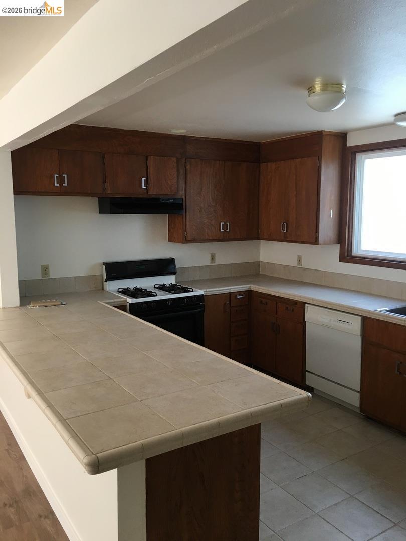 1641 Walnut Street Berkeley, CA 94709 - Photo 10 of 11 kitchen featuring tile counters, range with gas cooktop, a peninsula, and dishwasher