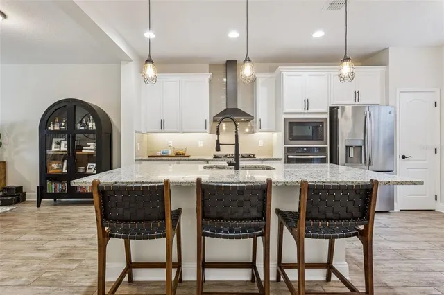 a kitchen with stainless steel appliances granite countertop a stove a refrigerator and a white cabinets