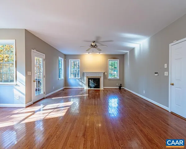 an empty room with wooden floor fireplace and windows