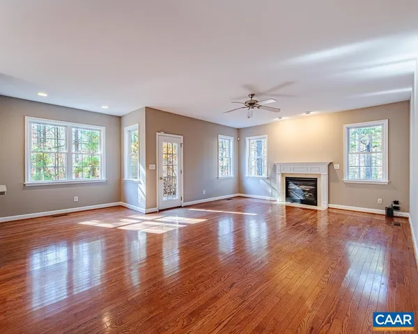 an empty room with wooden floor fireplace and windows