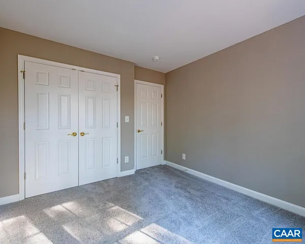 an empty room with chandelier fan and windows