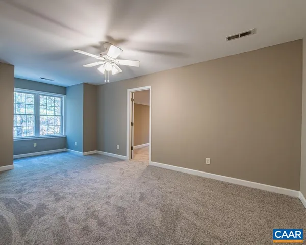 an empty room with windows and fan