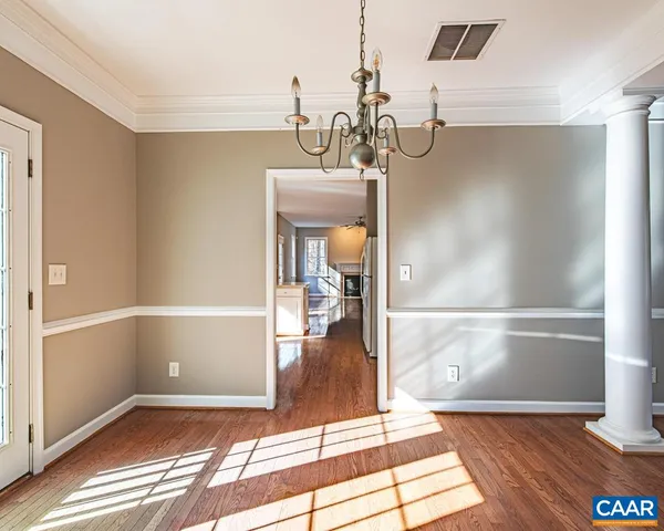 a view of a room with wooden floor and way to kitchen
