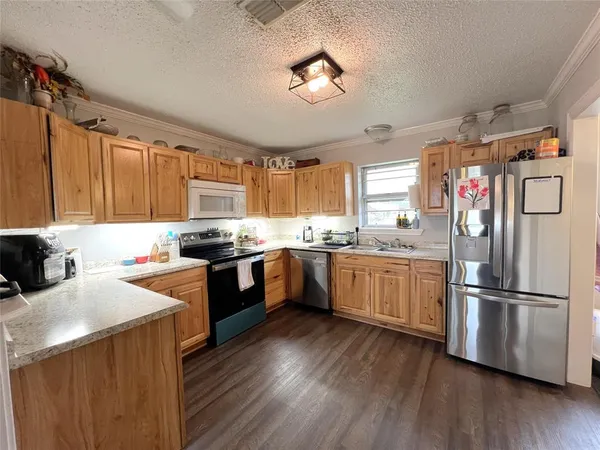 a kitchen with a refrigerator a sink dishwasher stove and wooden cabinets