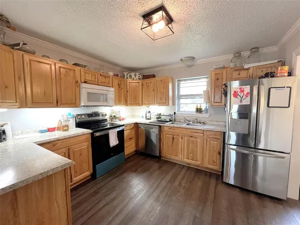 a kitchen with granite countertop stainless steel appliances a refrigerator cabinets and wooden floor