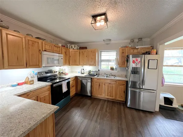 a kitchen with stainless steel appliances granite countertop a refrigerator a sink dishwasher a stove with wooden floor and cabinets