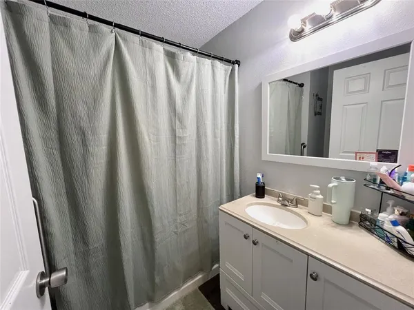 a bathroom with sink a mirror a vanity and shower curtain