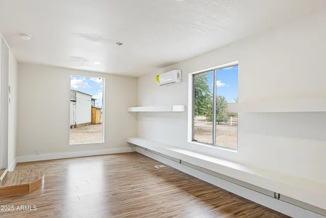 a view of an empty room with a window and wooden floor