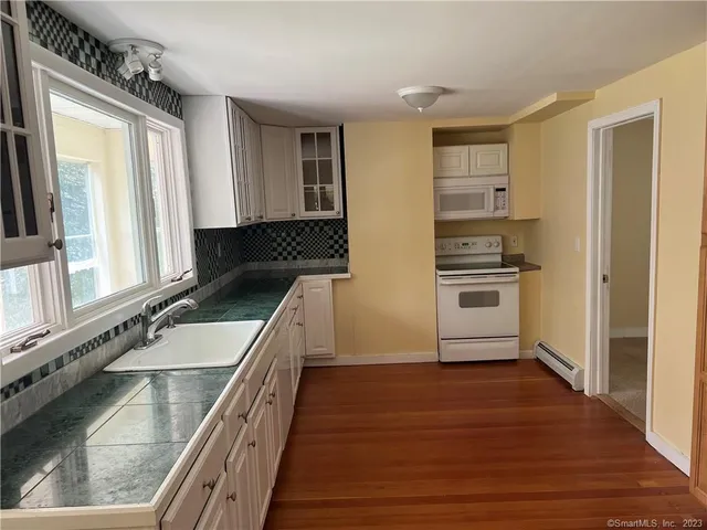 a refrigerator freezer sitting in a kitchen with stainless steel appliances wooden floor
