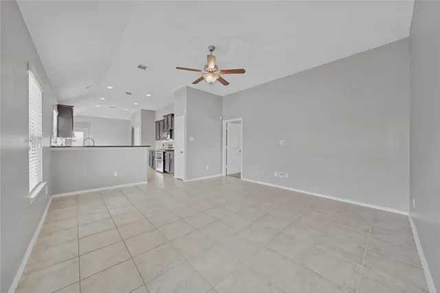 an empty room with a kitchen and a ceiling fan