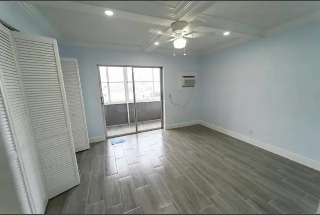 an empty room with wooden floor and fan