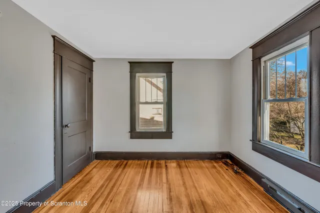 a view of an empty room with a window and wooden floor