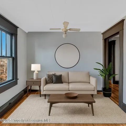 a living room with furniture a rug potted plant and a window