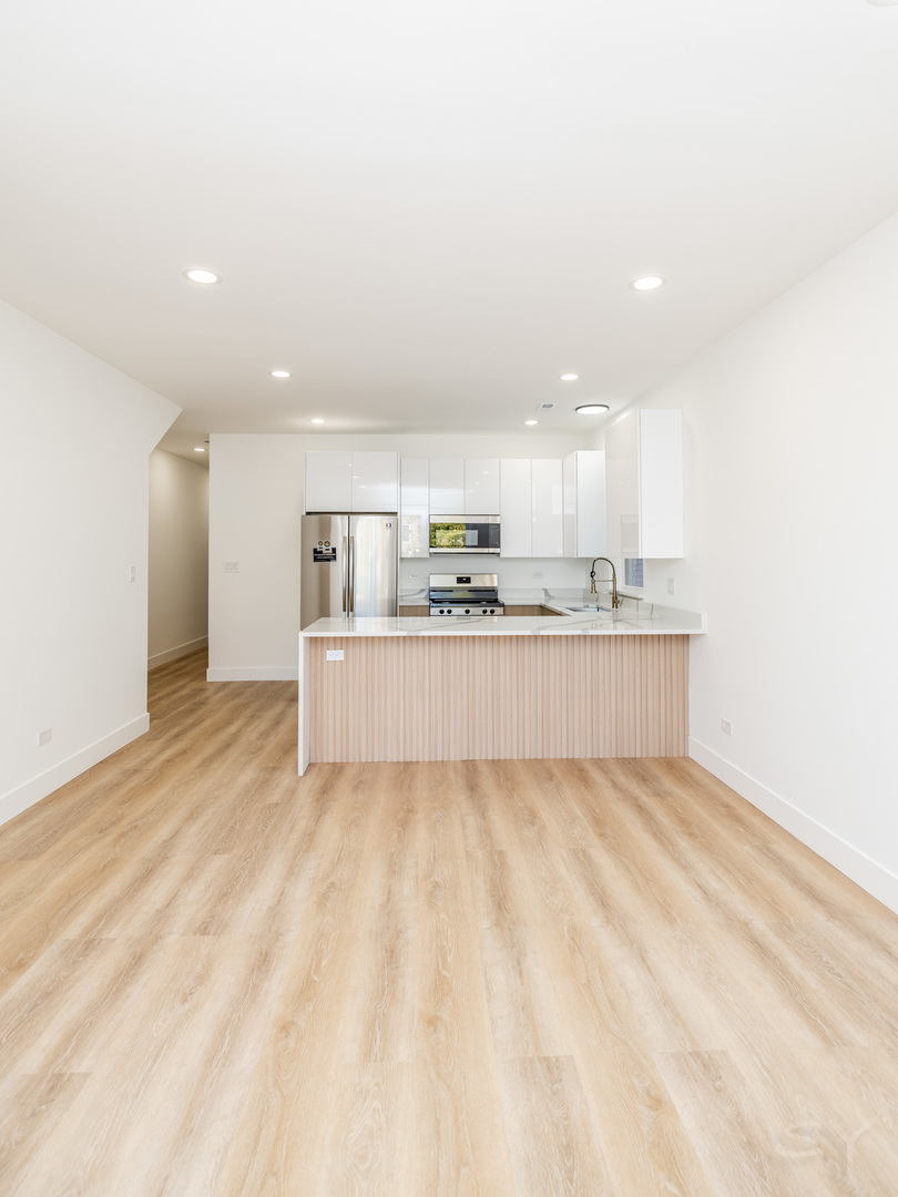 2949 West 25th Place, Unit 1 Chicago, IL 60623 - Photo 15 of 42 a large white kitchen with kitchen island a sink stainless steel appliances and cabinets