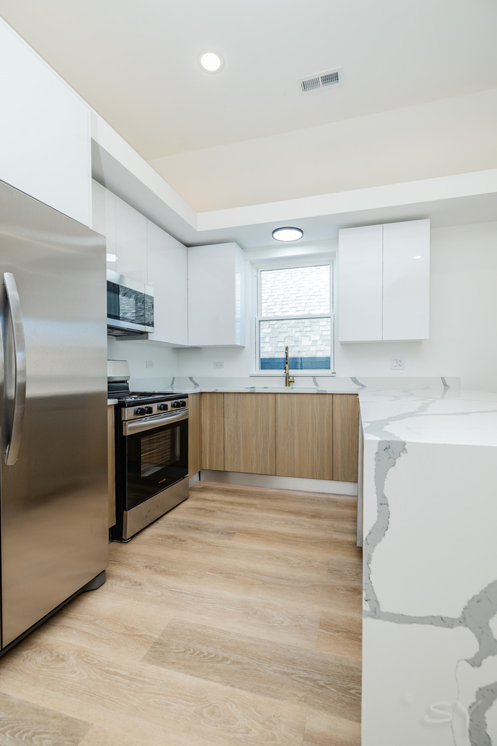 2949 West 25th Place, Unit 1 Chicago, IL 60623 - Photo 3 of 42 a kitchen with wooden cabinets and stainless steel appliances