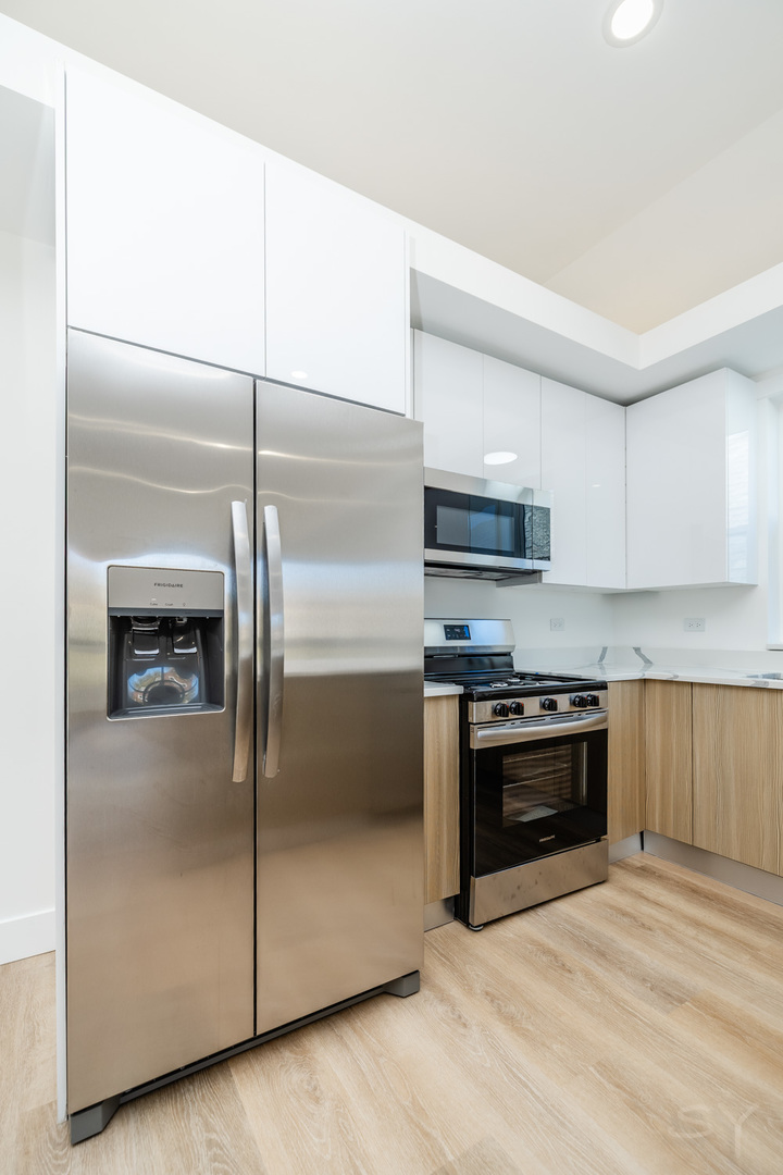 2949 West 25th Place, Unit 1 Chicago, IL 60623 - Photo 4 of 42 a kitchen with stainless steel appliances granite countertop a refrigerator a stove a sink and a microwave