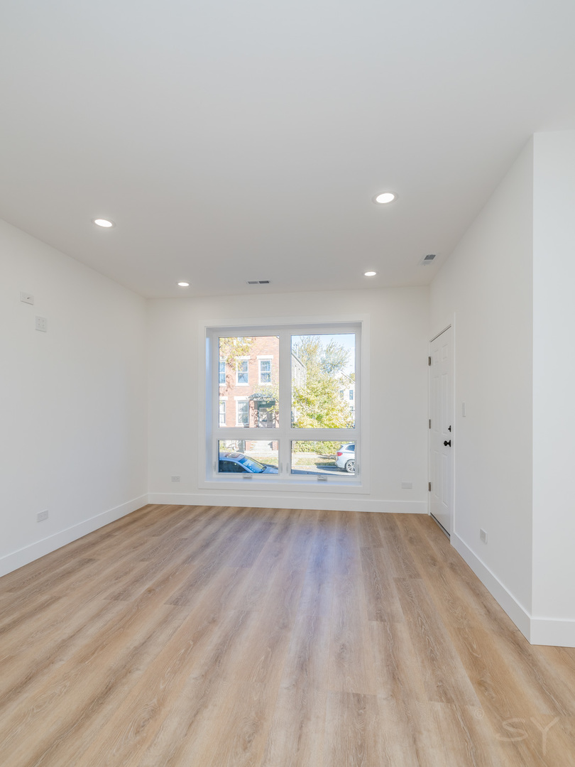 2949 West 25th Place, Unit 1 Chicago, IL 60623 - Photo 8 of 42 an empty room with wooden floor and windows