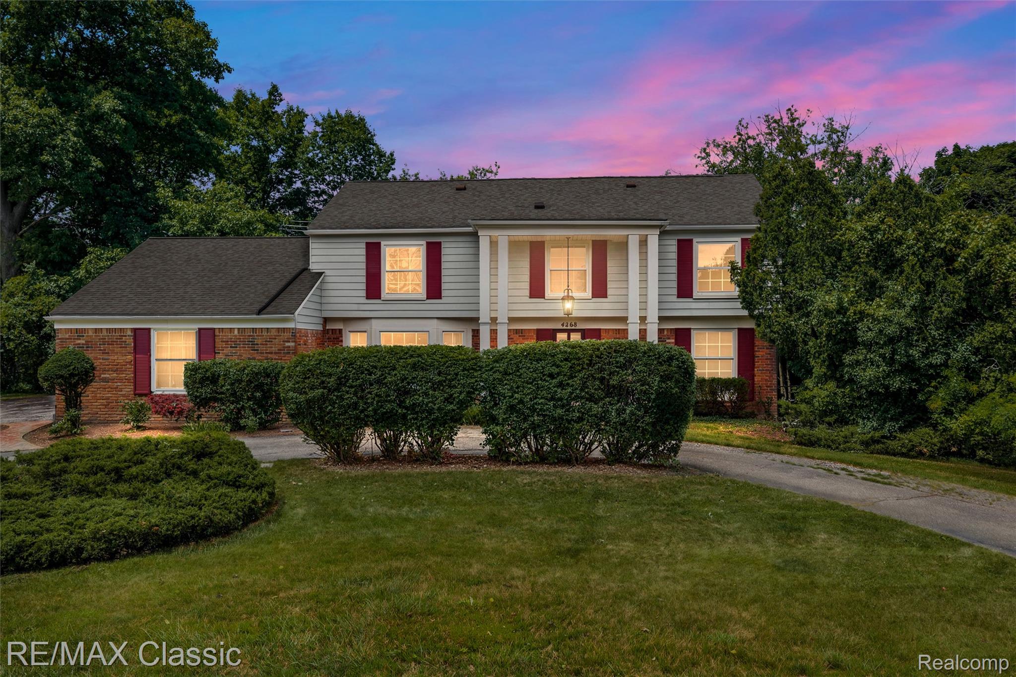 4268 Covered Bridge Road Bloomfield Hills, MI 48302 - Photo 1 of 35 Two-story residence featuring a combination of brick and siding exteriors, a prominent front portico, red window shutters, and a manicured lawn