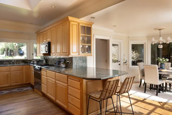 a kitchen with stainless steel appliances granite countertop wooden cabinets a dining table and chairs